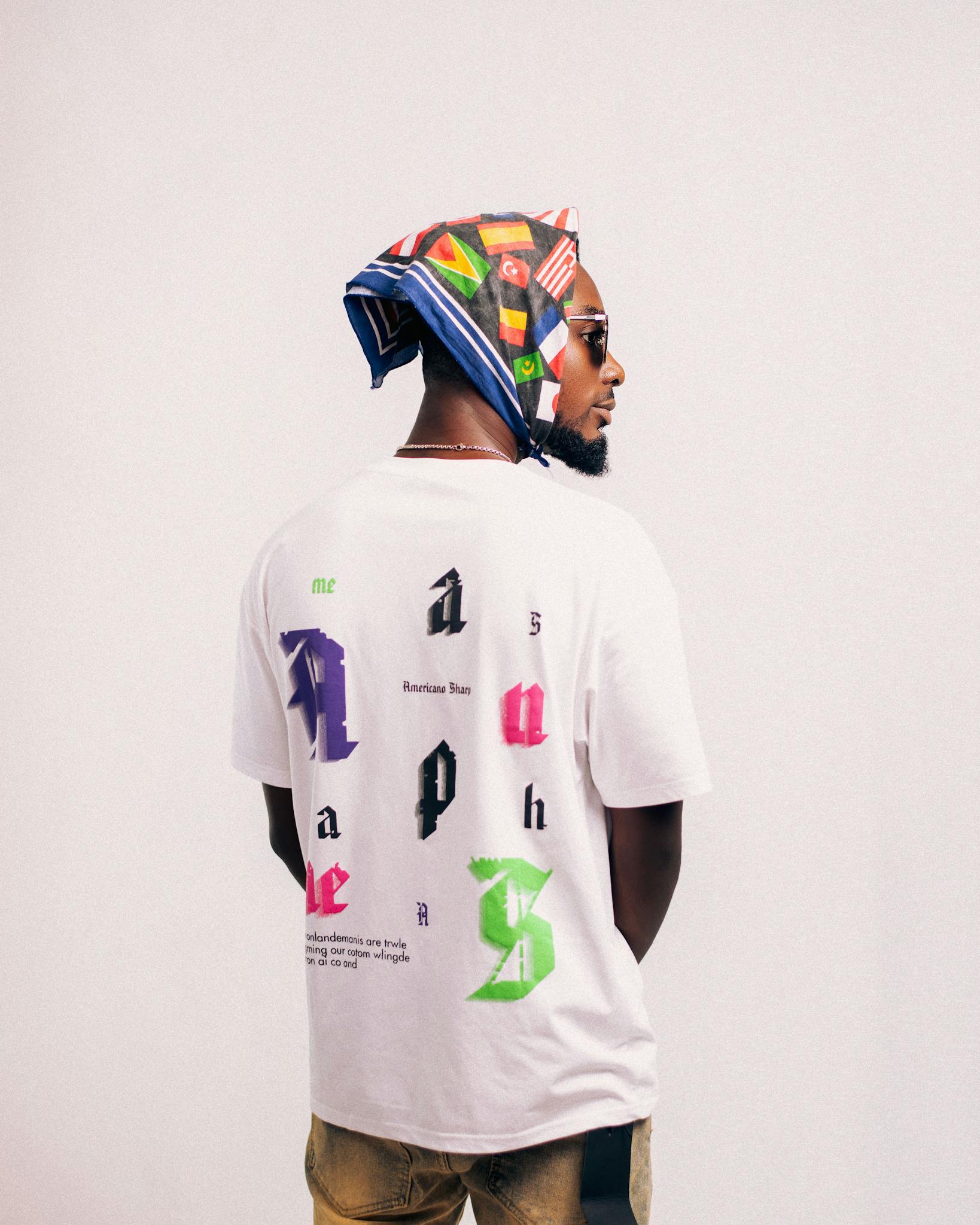 Stylish man wearing a graphic printed t-shirt and a colorful bandana with sunglasses.